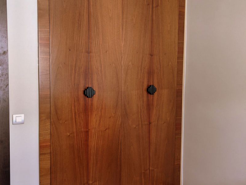 Armario de dos puertas de madera clara con tiradores negros